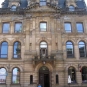 Colour photograph of an old brown sandstone four-storey building on a street